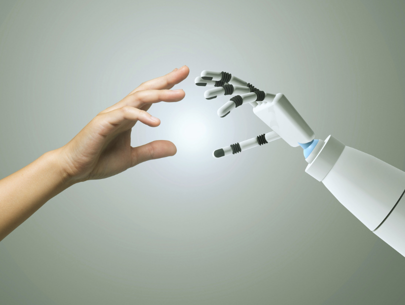 Eine menschliche Hand und eine Roboterhand strecken sich einander entgegen – Symbolbild für künstliche Intelligenz und Mensch-Maschine-Interaktion.