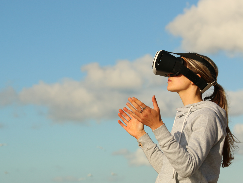 Mensch draußen mit VR Brille und die Hände aus einander