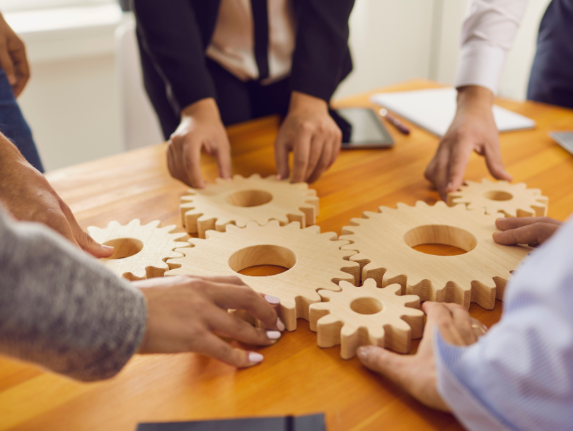 Menschen legen einen Radpuzzle auf ein Holztisch