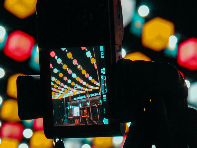 Verschiedenfarbige Laternen am Himmel und eine Kamera davor, die versucht, ein Bild davon zu machen.